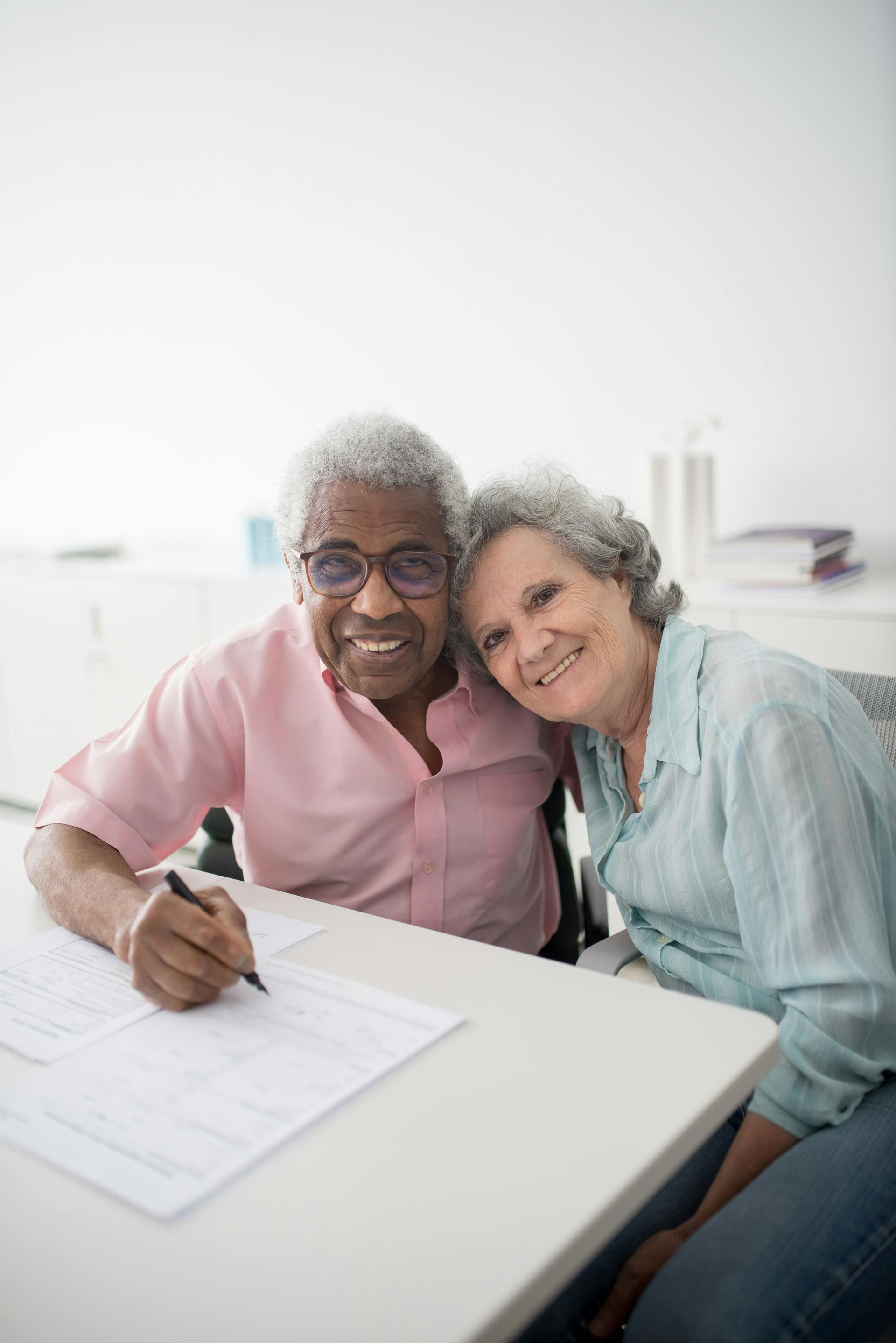 Two people smiling at a desk, signing paperwork in a bright office