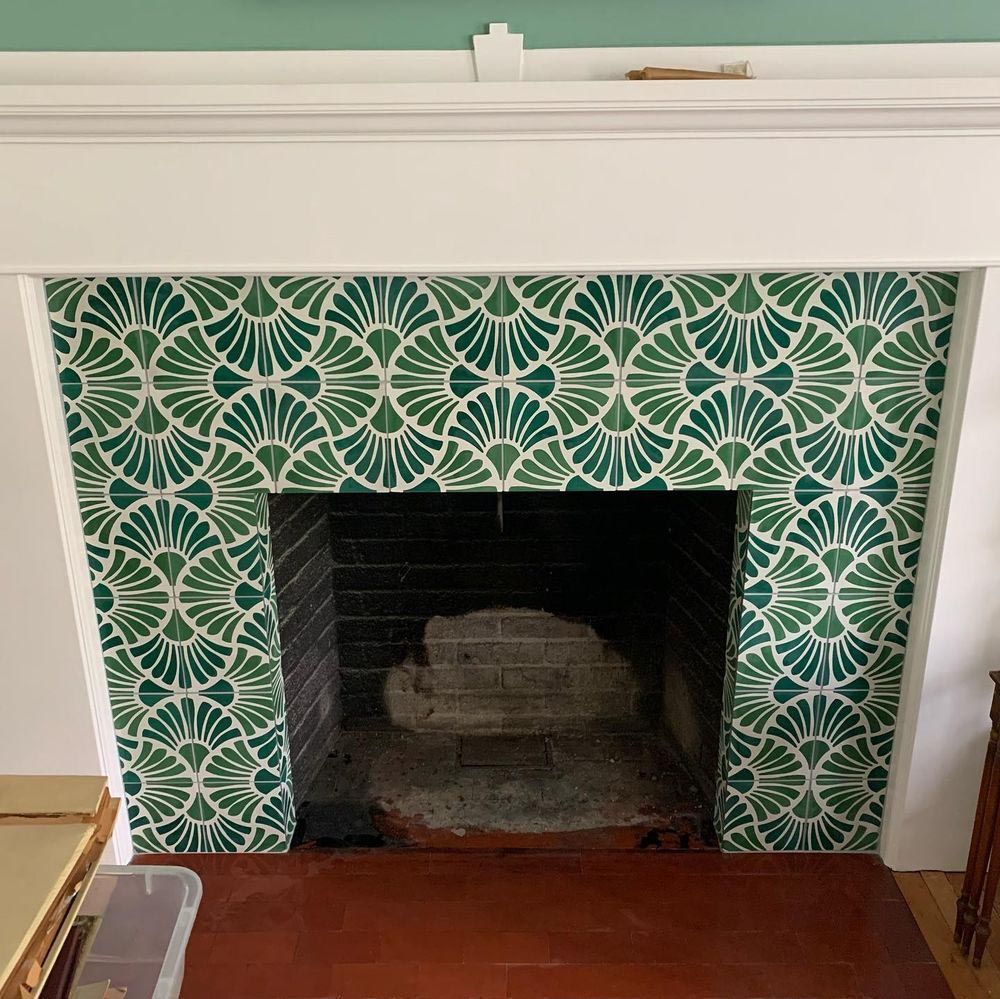 A fireplace with a green tile design on the wall.