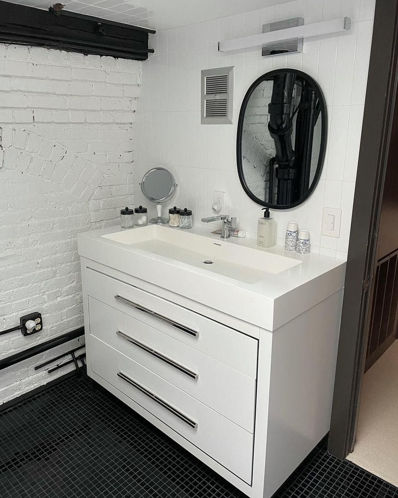 A bathroom with a sink , mirror and drawers.