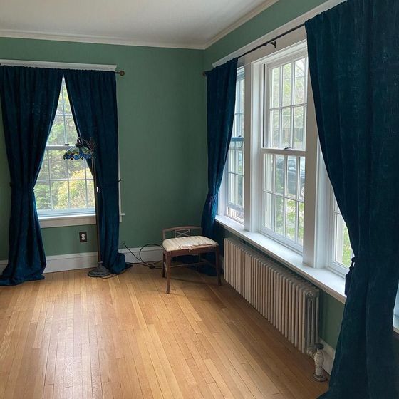 A living room with green walls and blue curtains