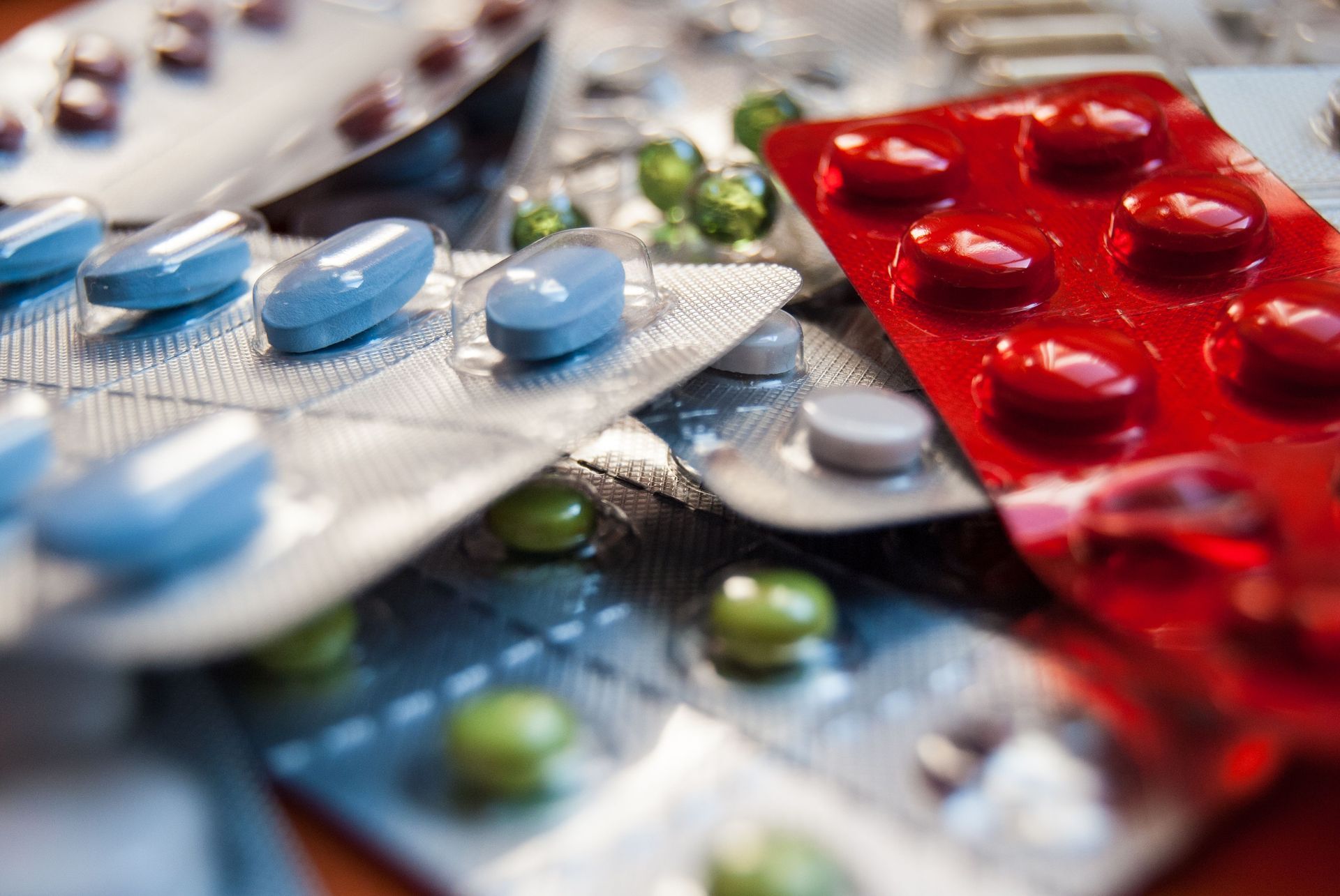 Person in blue medical scrubs taking a pill from a pill organizer.