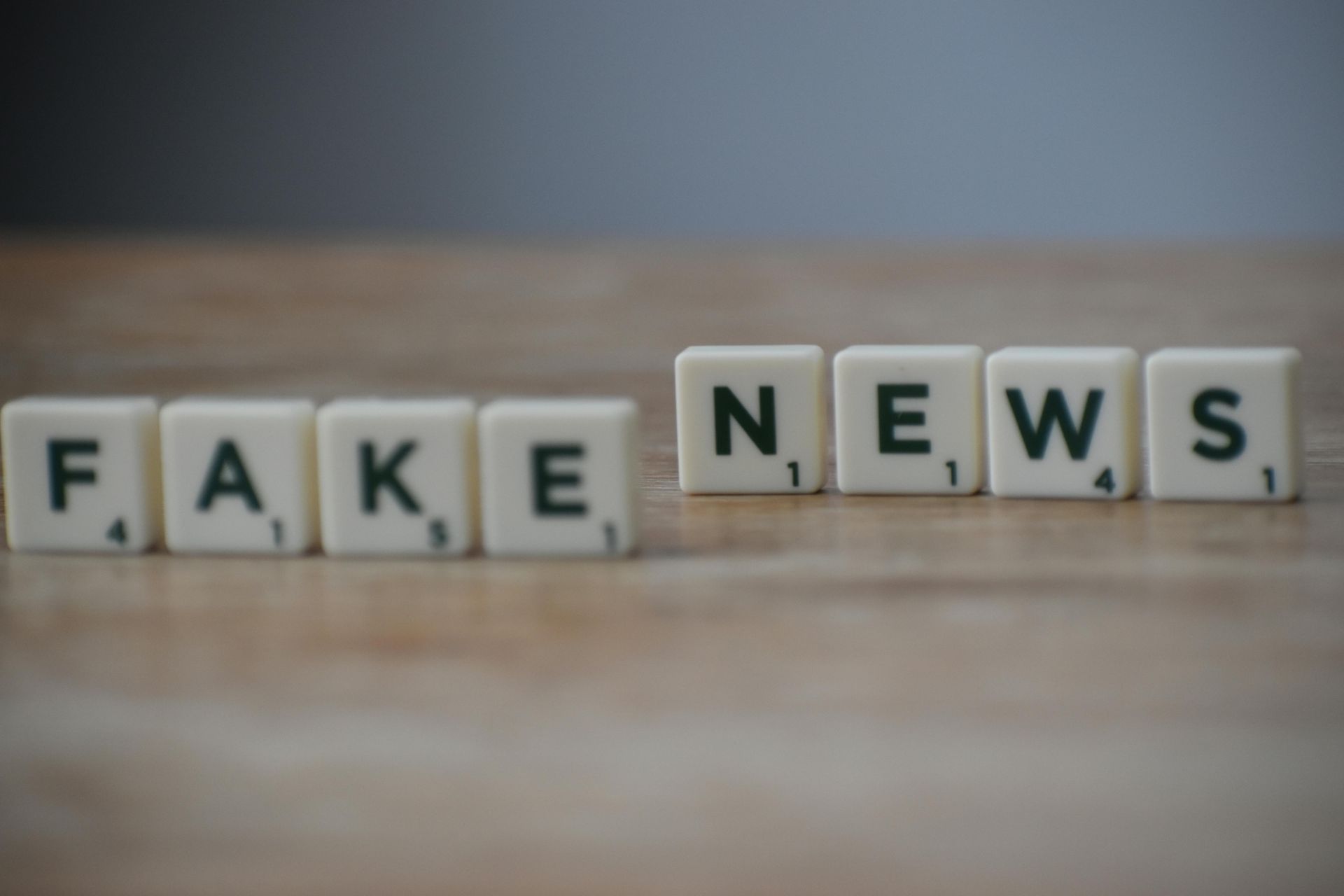 A seesaw with “TRUTH FACTS” on the left and “FAKE NEWS” on the right against a blue background