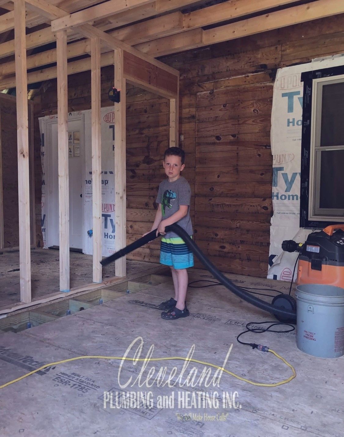 A young boy vacuuming a construction site. He's wearing shorts and a t-shirt, with a focused expression.