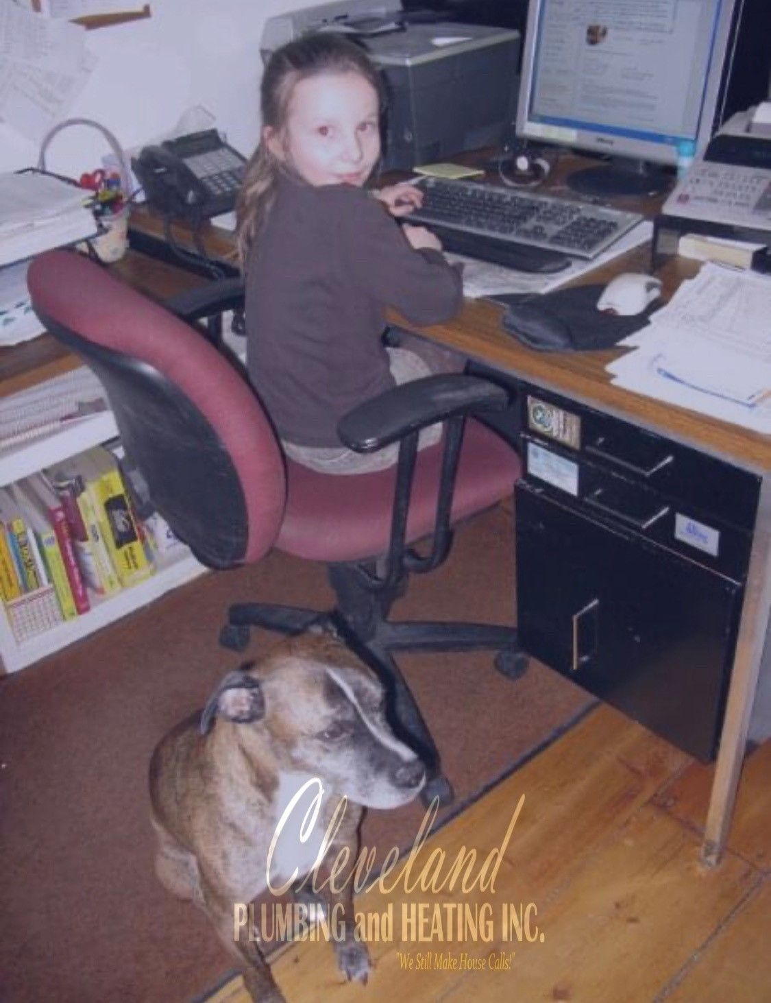 Girl at desk with dog; brown top, computer, phone. Brown and white dog. Office setting, Cleveland Plumbing logo.