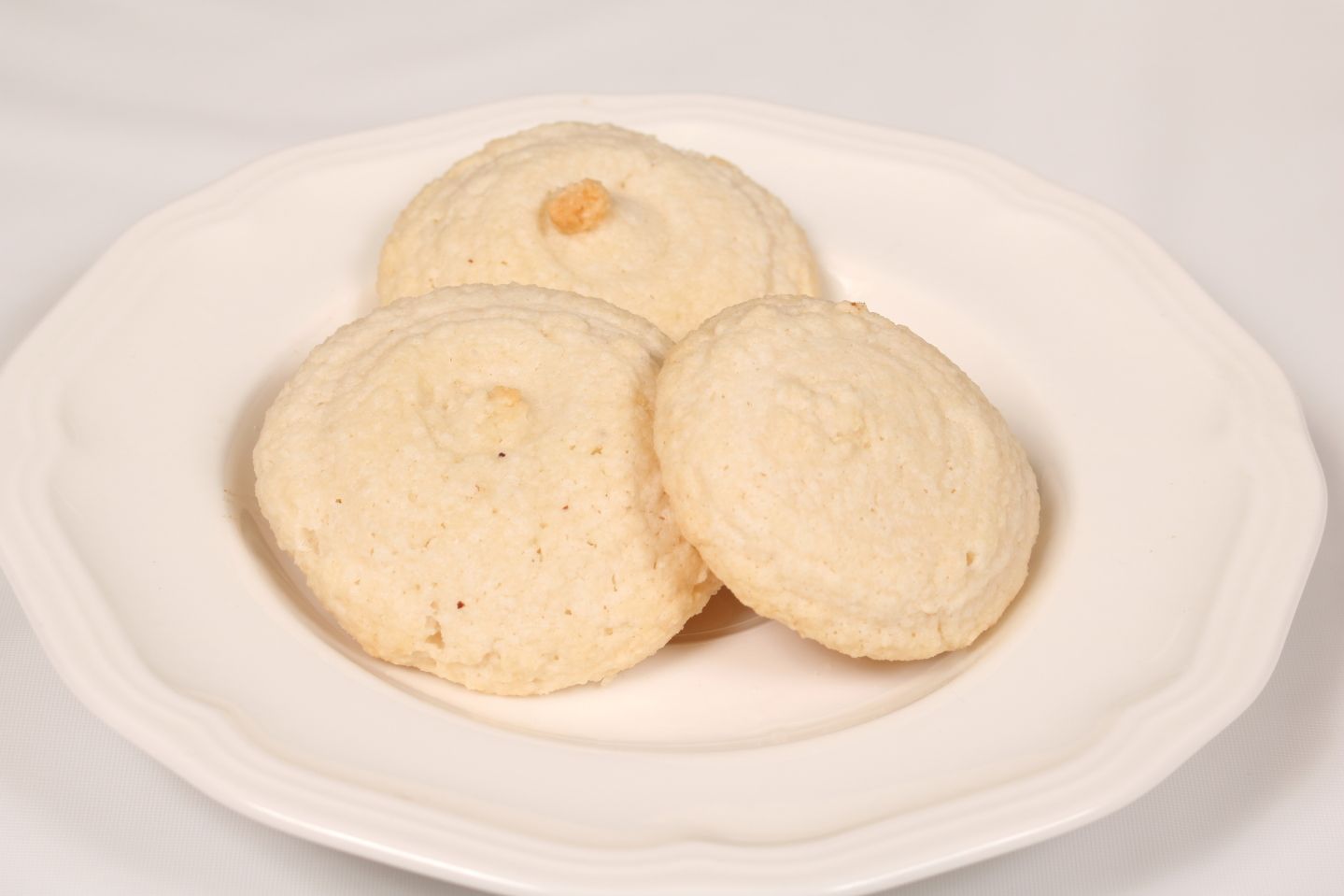 Three round, light-colored cookies arranged on a white plate.