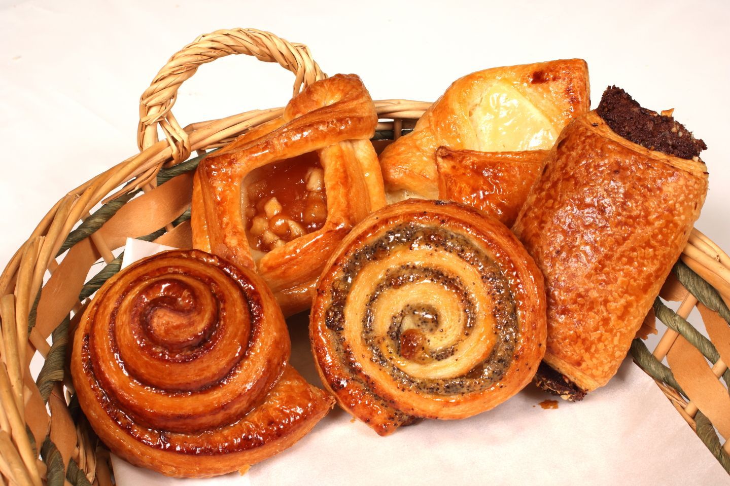 Basket of assorted pastries: cinnamon rolls, fruit danish, and filled pastries.