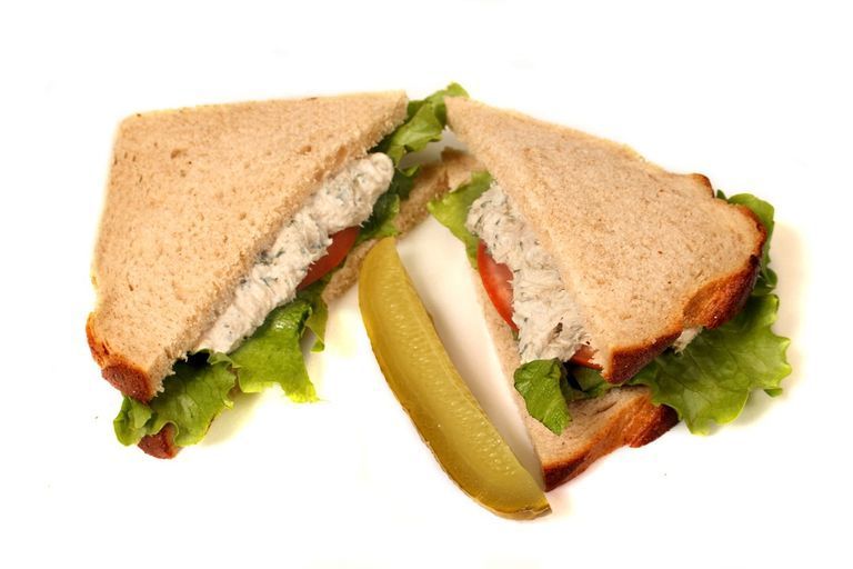 Sandwich cut in half with lettuce, tomato, and pickle.