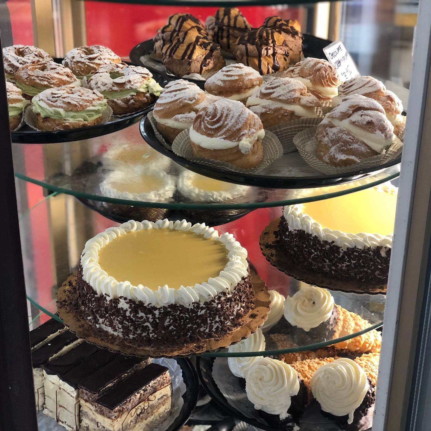 Pastries displayed in a glass bakery case: cakes, cream-filled buns, and other baked goods.