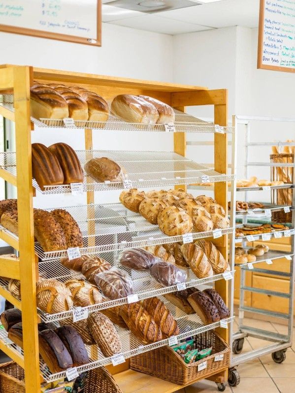Wooden shelves filled with various loaves of bread in a bakery.