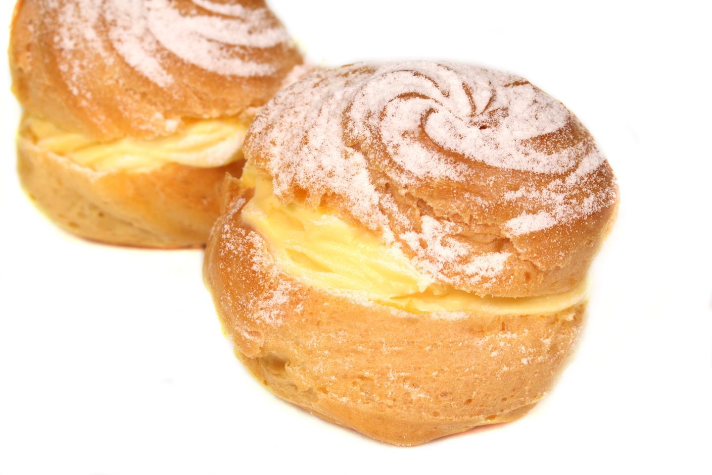Two cream puffs dusted with powdered sugar, filled with yellow cream.
