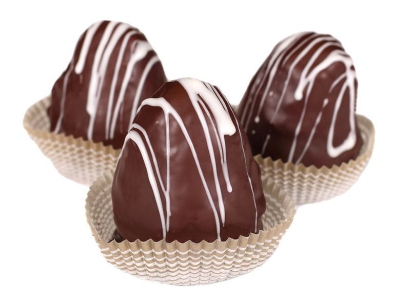 Three heart-shaped chocolate treats, dark chocolate shell with white drizzle, in paper cups.