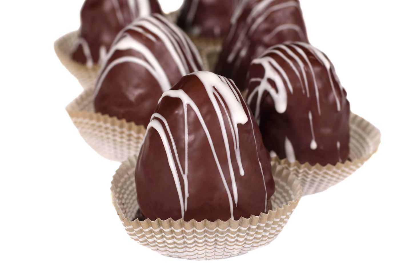 Chocolate pastries with white icing drizzle in paper cups.