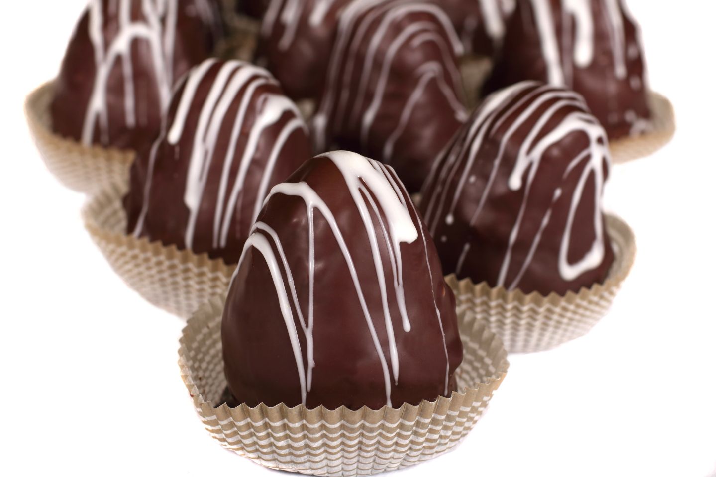 Chocolate confections in paper cups, drizzled with white icing.