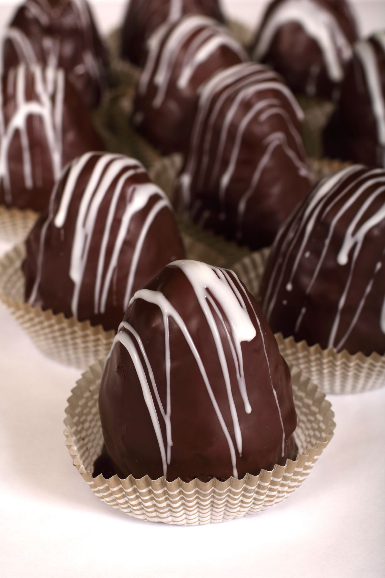 Chocolate heart-shaped truffles in paper cups, drizzled with white icing.