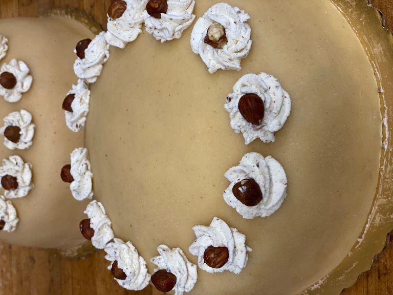 Two round, light-colored cakes with white frosting swirls and hazelnuts.