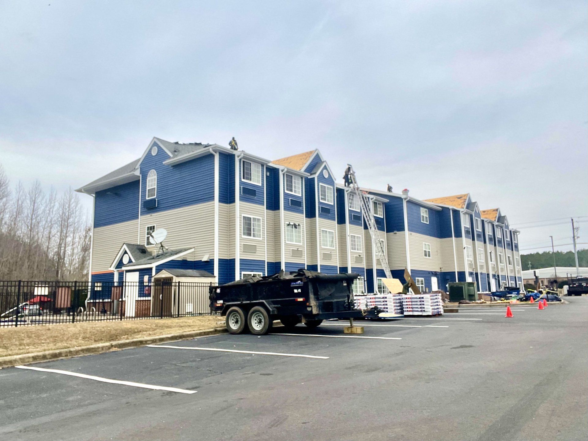 A commercial roofing project on a multi-story apartment building, with equipment on site for roof replacement in North Carolina.