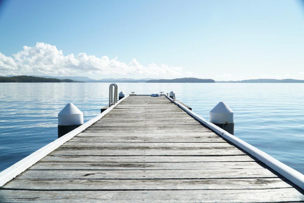 A Wooden Dock Leading Into A Body Of Water — Triple S Scaffolding In Port Macquarie, NSW