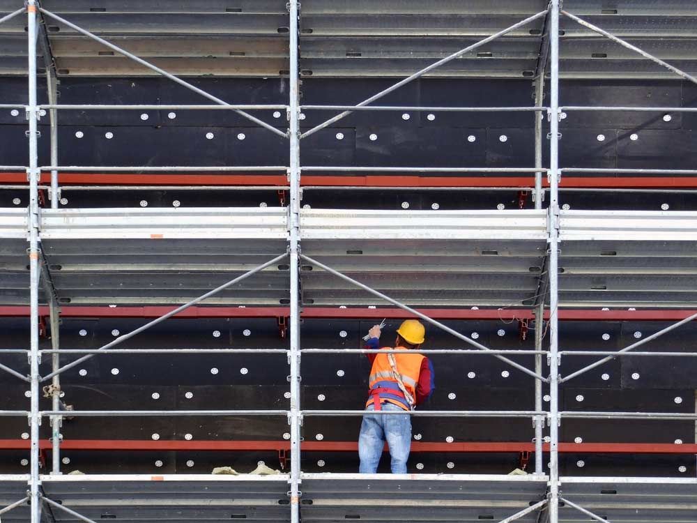 A Construction Worker Is Standing On Top Of A Scaffolding — Triple S Scaffolding In Wauchope, NSW
