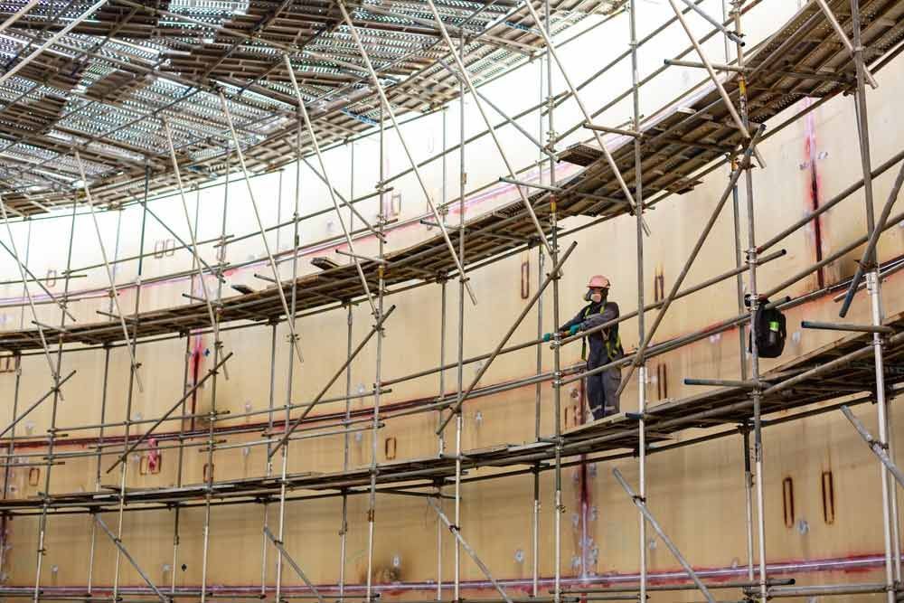 A Construction Worker Is Standing On Top Of A Scaffolding — Triple S Scaffolding In Laurieton, NSW