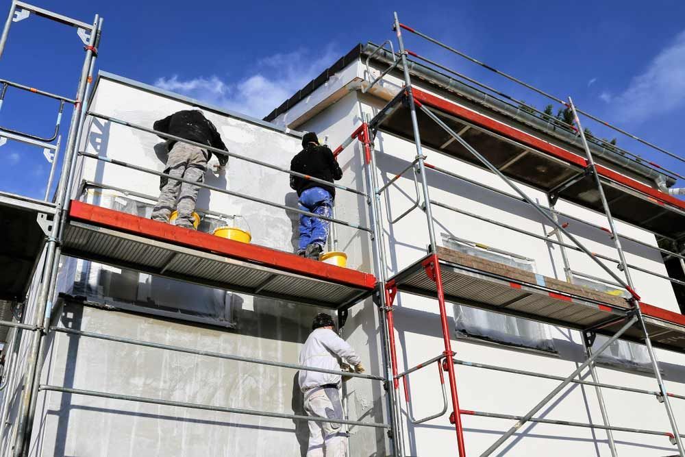 Two Men Are Painting The Side Of A Building On Scaffolding — Triple S Scaffolding In South West Rocks, NSW