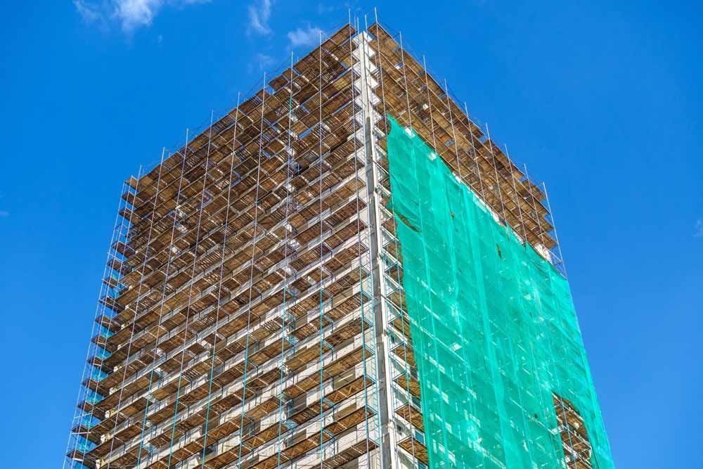 A Tall Building Under Construction With Scaffolding And A Blue Sky In The Background — Triple S Scaffolding In Forster, NSW