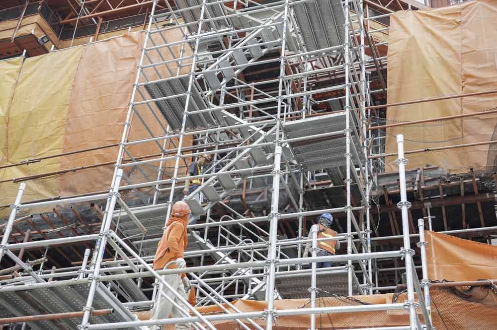 A Group Of Construction Workers Are Standing On Scaffolding On Top Of A Building — Triple S Scaffolding In Forster, NSW