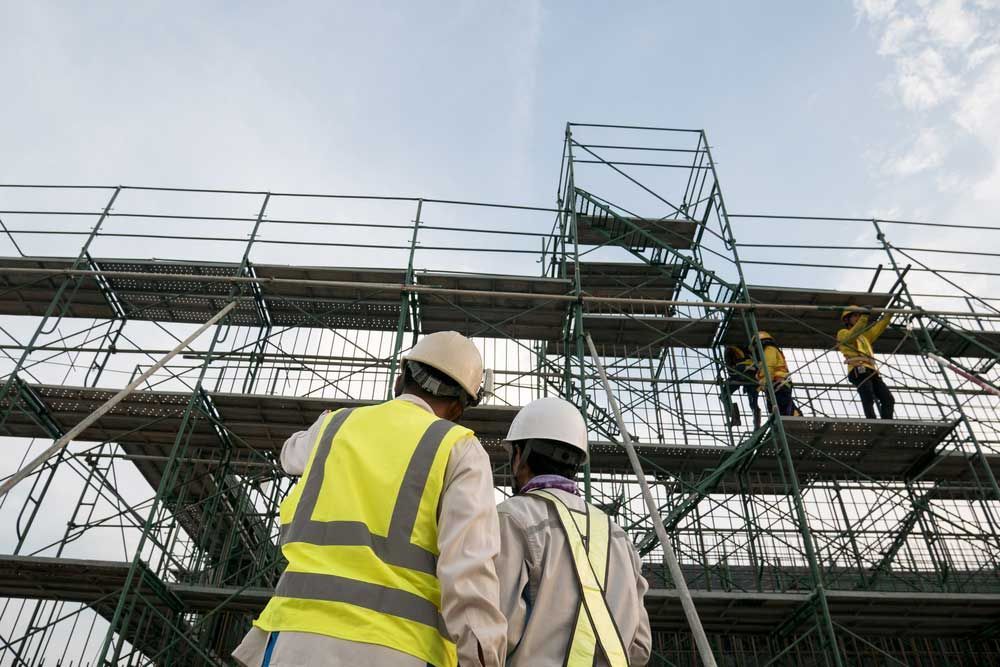 A Couple Of Construction Workers Are Standing On Top Of A Scaffolding — Triple S Scaffolding In Port Macquarie, NSW