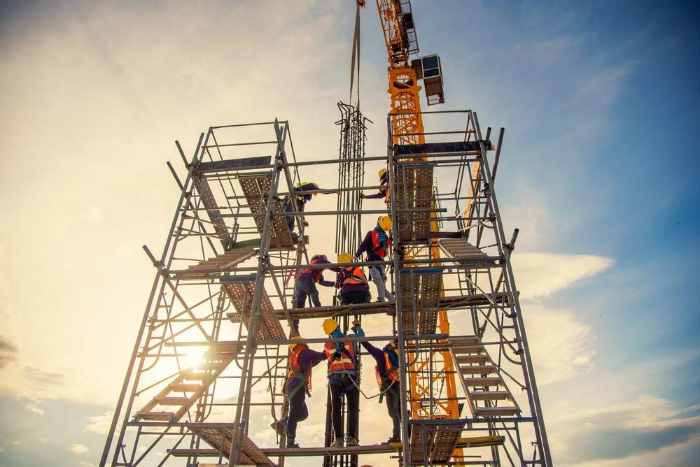A Group Of Construction Workers Are Working On A Crane At A Construction Site — Triple S Scaffolding In Kempsey, NSW