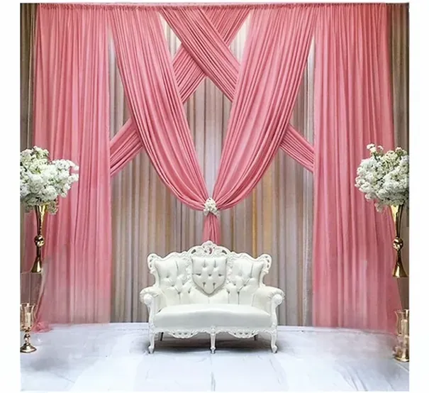 Pink draped backdrop for a white sofa, flanked by floral arrangements.