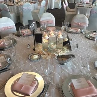 Wedding reception table setting with pink accents and floating candle centerpiece.