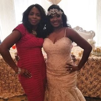 Two women pose for a photo: one in a red dress, one in a wedding dress, at an event.