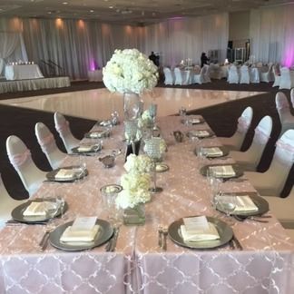 Formal wedding reception table setting with floral centerpieces and pink tablecloth.