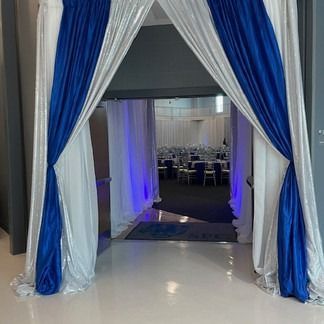 Blue and white draped doorway with a glimpse of a decorated banquet hall.