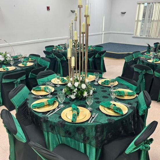 Elegant banquet tables set with gold chargers, green napkins, and tall candleholders.