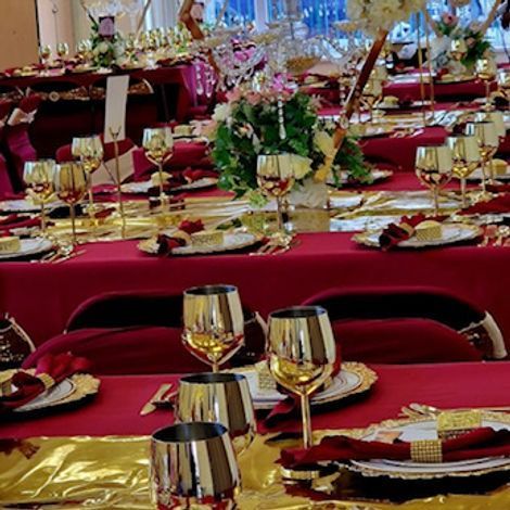 Red and gold banquet tables, set for dining, with floral centerpieces and glassware.