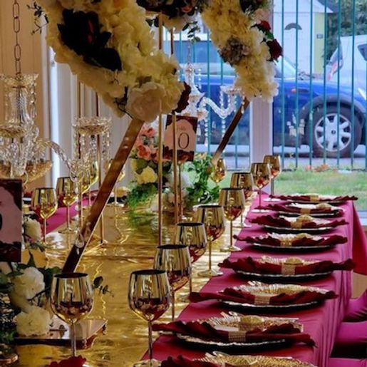 Elegant table setting with gold accents, red linens, and floral arrangements.