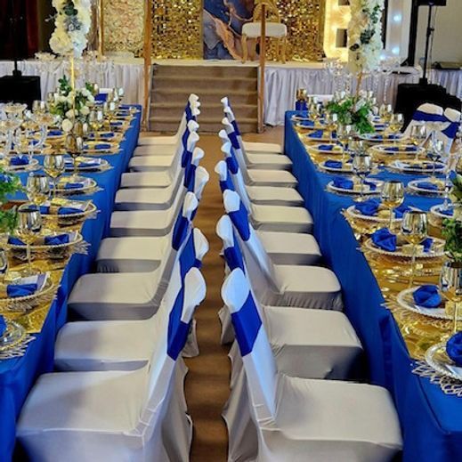 Formal event: rows of tables set with blue and gold decor, white chairs with blue accents.