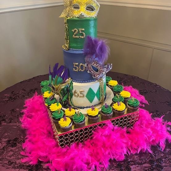 Mardi Gras-themed tiered cake with masks and cupcakes, purple, green, gold.