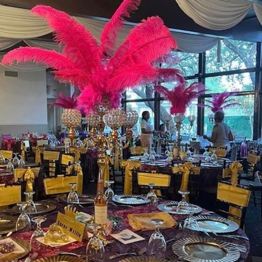 Mardi Gras-themed dining room with hot pink feather centerpieces and gold accents.