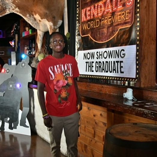 Person in red shirt poses next to a sign that says 