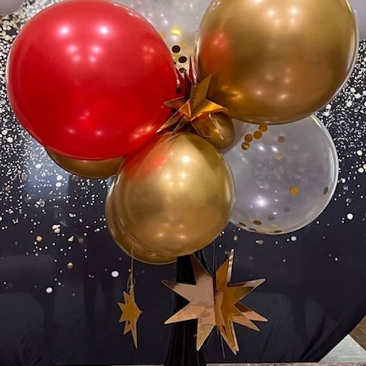 Red and gold balloons with gold stars against a black and gold background.