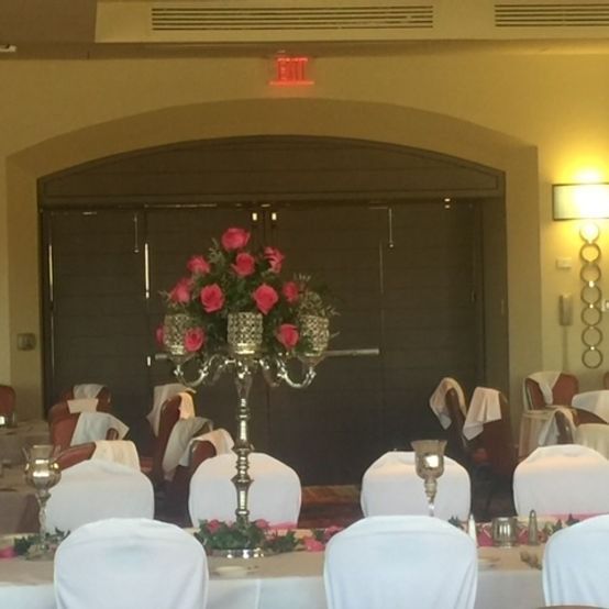Formal dining room set for an event, featuring a large floral centerpiece and white chair covers.