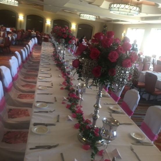 Long table set for a formal event, with pink roses and silver candelabras.