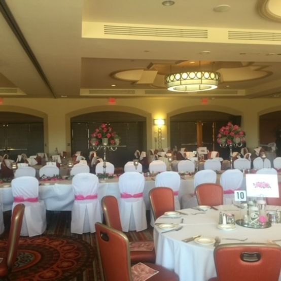 Banquet hall, tables set with white tablecloths, pink accents, and floral centerpieces.