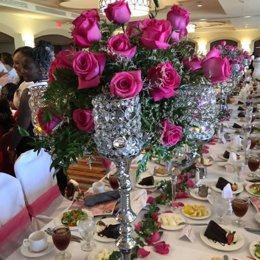 Formal table setting with pink roses centerpiece and seated guests.