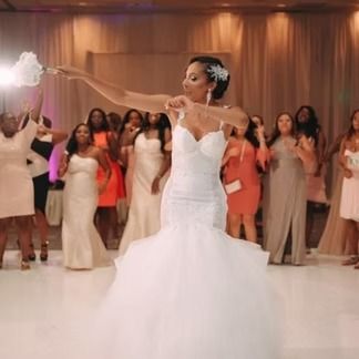 Bride in a white dress throws her bouquet at a wedding reception.