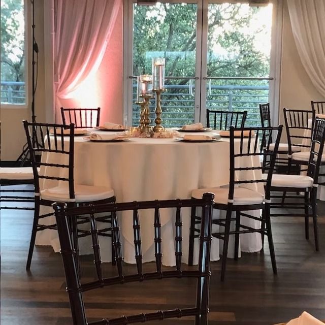 Elegant dining room with round table, decorated with candles, surrounded by chairs, near a window.