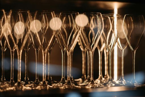 Empty champagne flutes lined up, with blurred background lights.