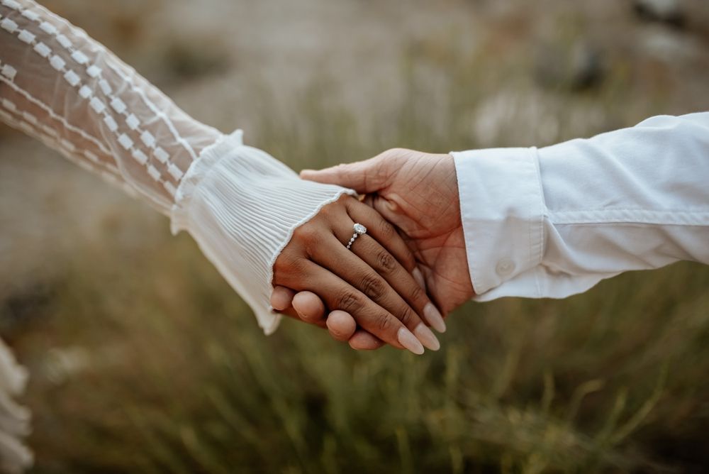 Hands of a person being proposed to, ring being placed on their finger, close-up.