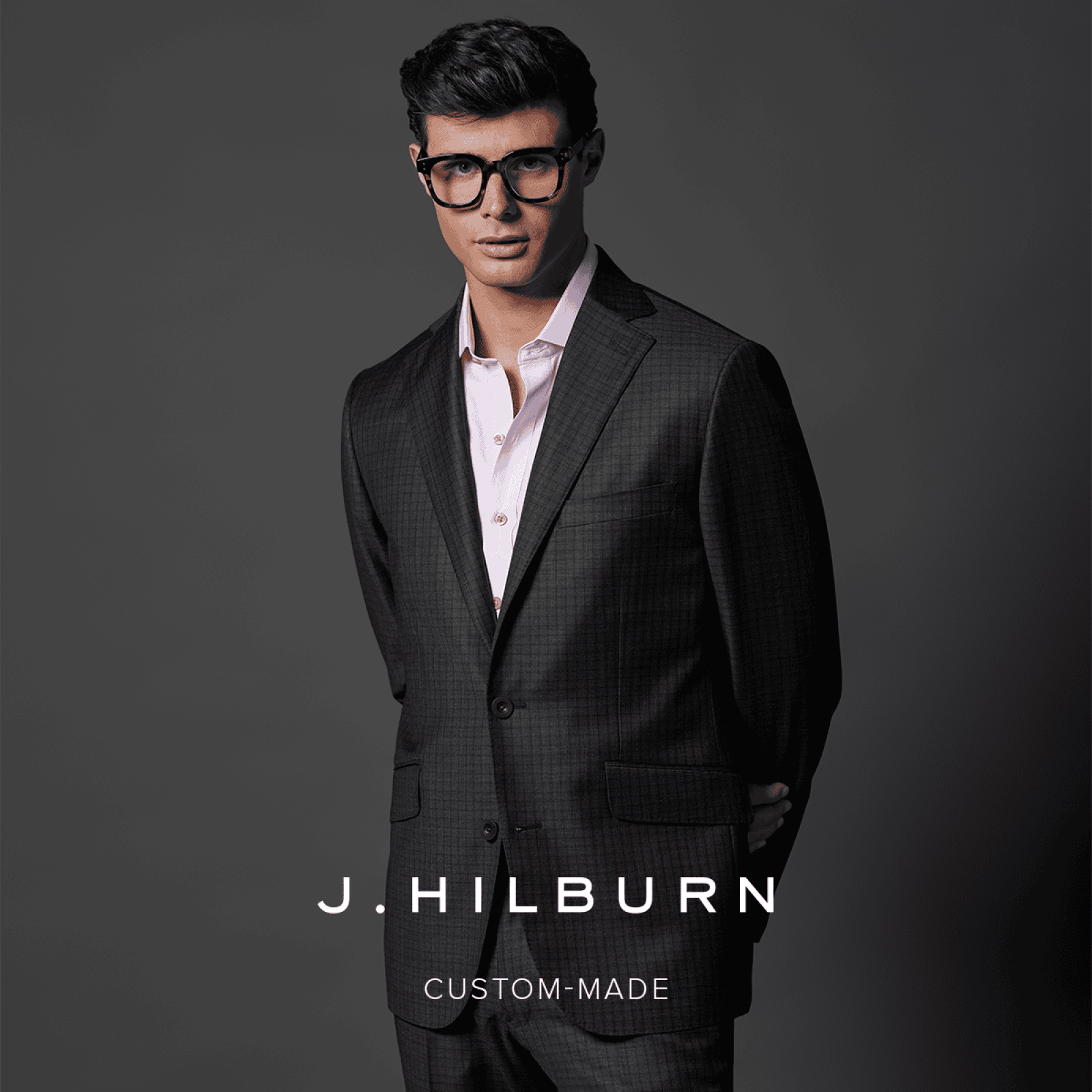 a man is walking down a runway wearing a plaid suit and tie .